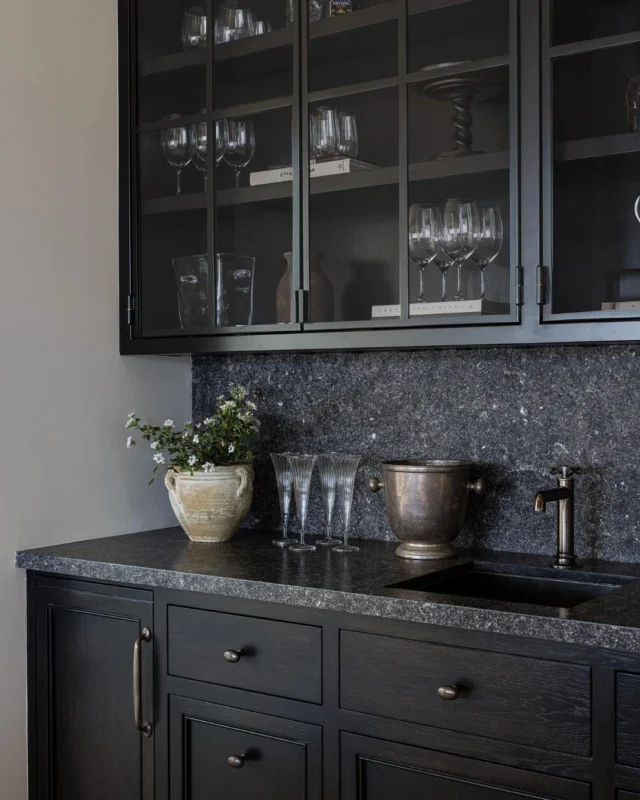 Just beyond the kitchen, the bar at #mgdxlido strikes a moodier note with dark limestone and steel-framed glass and oak cabinetry. We love the touch of contrast it adds to this coastal California great room. #mindygayerdesign { Image by: @vlentine, Architect: @brandonarchitects, Builder: @longmanconstruction }